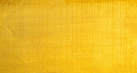 Fototapeta premium Gold wall texture background. Yellow shiny gold foil paint on wall surface with light reflection
