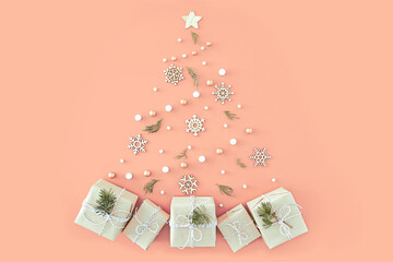 Festive composition with Christmas tree made of small gifts and snowflakes on solid soft pink background. Trendy pastel neutral xmas template. Top view, flat lay style, copy space for text.