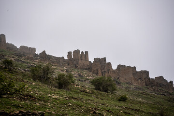 Fototapeta premium the ruins of an ancient alpine settlement in the mountains of Dagestan against the backdrop of mountains and blue sky