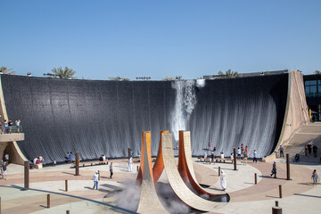 artificial waterfall with water running and people standing in the water