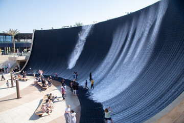 artificial waterfall with water running and people standing in the water