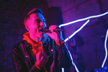 A singer man at the scene with the microphone in the neon lights concept.
