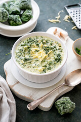 Creamed spinach with garlic and cheese in a white bowl on dark background.