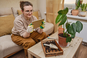 Woman gardener holds tablet in her hands for online learning on plants. Blogger shoots videos and photos of home gardening for an online blog