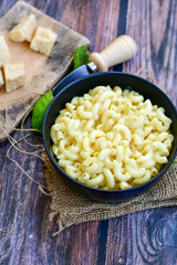 Macaroni in cheese sauce. Home made mac and cheese  pasta  Mac and cheese, american style macaroni pasta with cheesy sauce  on dark rustic table