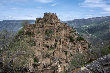 the ruins of an ancient alpine settlement in the mountains of Dagestan against the backdrop of mountains and blue sky