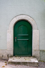 Old wooden green entrance door. Large rustic vintage entrance door in a concrete building in Europe. Front view, no people