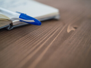 Blue ballpoint pen on notepad on walnut wood table with copy space