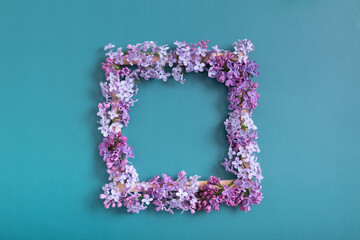Easter spring composition on a turquoise background. Lilac flowers square with copy space top view. Summer, spring floral concept