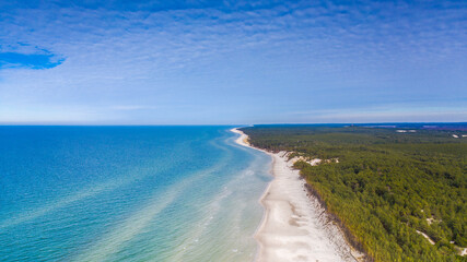 Fototapeta na wymiar Aerial landscape of the sandy beach, clear sea water and green forest in a sunny day. Blue sky and blue water.