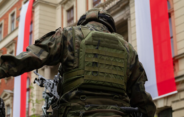 Polish army soldier during 3 May Constitution Day ceremonial patriotic parade. Military troops at celebration of the 3rd May National Holiday, with flags of Poland in background.