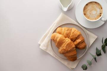 Croissants with chocolate and coffee cup on bright background. Copy space