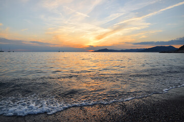 incredible colors and lights, a romantic sunset on the beach facing the sea in the magnificent Liguria
