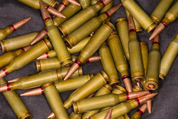 Heap of the rifle cartridges on a black textile surface