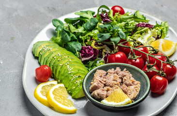 Tuna fish salad on light background. Lettuce, cherry tomatoes, avocado and red onions. Clean healthy detox eating. Vegan vegetarian food. Making healthy salad. top view