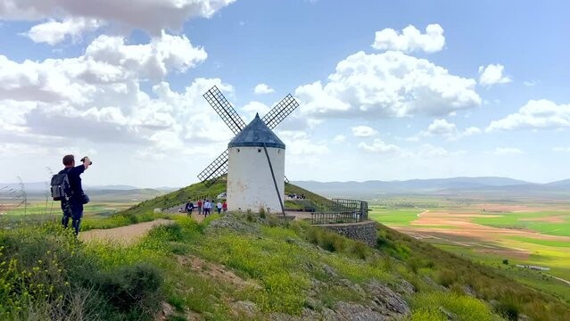 Scenic vision of a tourist photographer taking a picture of an old windmill on a sunny day in Consuegra, Spain.