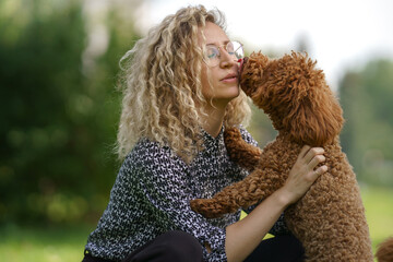 girl and dog in park. Walking with pet. happy poodle kissing girl