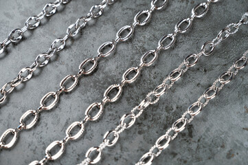 Set of different chains on a concrete background. Chain connection, types of metal chains