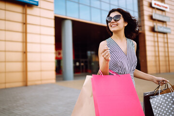 Shopping time. Young woman with shopping bags near the mall. Consumerism, sale, purchases, shopping, lifestyle concept. Summer.