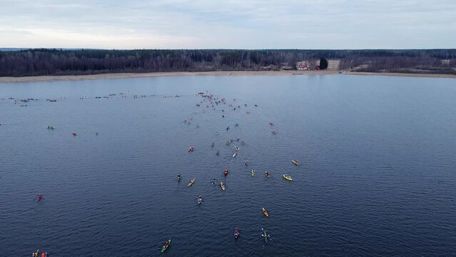 Aerial drone video of kayakers competition on a open water. Water sports. Canoe and kayak. Paddling and rowing. Pro athlete women and men teams. Blue lake. Beautiful spring landscape. 