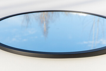 A round or oval mirror with a reflection of the blue sky and white clouds. Close-up. Isolated on a white background