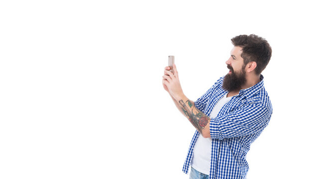 happy brutal bearded man taking picture with phone isolated on white background with copy space