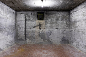 Front view of reinforced concrete wall with a small window for air. Scene illuminated by a white...