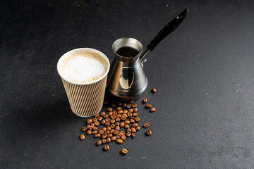 A cup of coffee and coffee beans on a dark stone background. View from above. Copy space - image