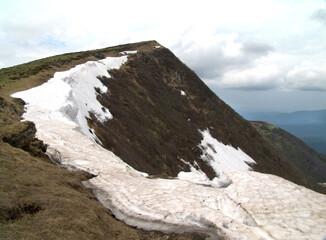 Spring snow melting in the mountains, darkened under the rays of the sun.