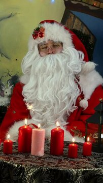 Merry Santa waving burning sparkler in his hands sitting. Vertical video.