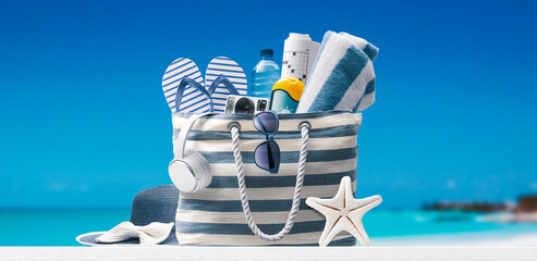 Beach bag with accessories and tropical beach - obrazy, fototapety, plakaty