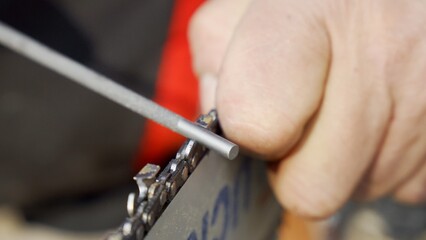 Chainsaw chain sharpening with a round file. Closeup macro view.