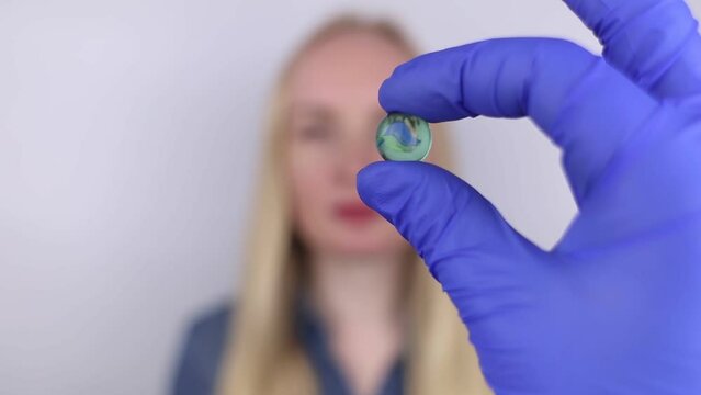 Conceptual shot of an eye crystalline lens replacement. Ophthalmic surgery. Return of sight. Removal of cataracts. Surgical intervention in the eyeball. Doctor holds the implant near the patient