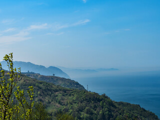 View from the observation deck to the sea and mountains. The mountains are shrouded in clouds and mist. Morning dawn in the mountains. Mountain landscape. Skyline. Blue sky. copy space