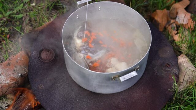Cooking fish soup over an open fire, camping. 