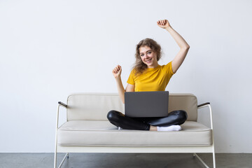 Young woman with credit card and laptop sitting on sofa at home