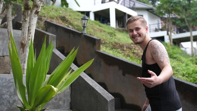 Young man inviting someone to come on up stair in tropical island