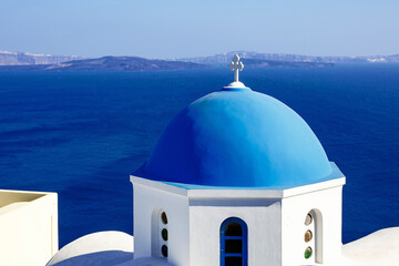 Fototapeta na wymiar Greek orthodox church with blue dome and sea in Oia in Santorini, Greece.