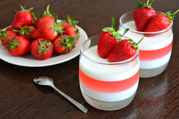 jelly dessert with milk and strawberry in drinking glass on wooden background