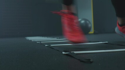 Caucasian woman in sportswear doing agility ladder drill workout at the gym, focus, speed and strength training, ground level shot.