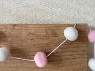 White and pink balls hanging on a string over a wooden board