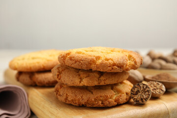 Fototapeta na wymiar Nutmeg seeds and tasty cookies on wooden board, closeup