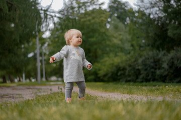 cute funny little girl learning to walk in park