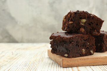 Delicious brownies with nuts on white wooden table, closeup. Space for text