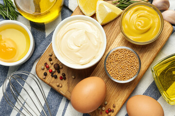 Bowl with fresh mayonnaise and ingredients on kitchen towel, flat lay