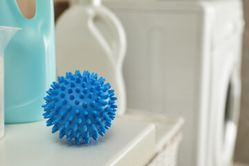 Dryer ball and laundry detergents on white table indoors, closeup