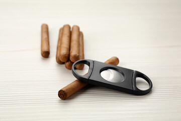 Cigars and guillotine cutter on white wooden table