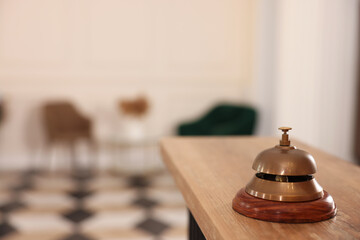 Hotel service bell on wooden reception desk. Space for text