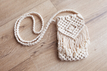 Handmade macrame bag  on wooden background. ECO friendly natural macrame cotton bag for woman. Hobby knitting handmade macrame. Modern summer concept.