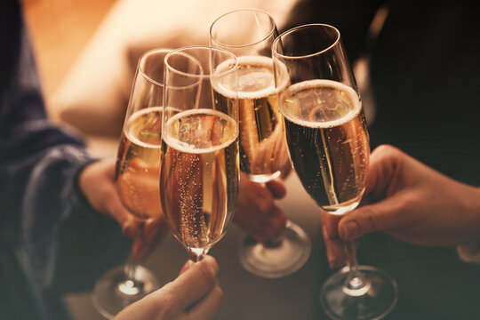 People clinking glasses with sparkling wine indoors , closeup
